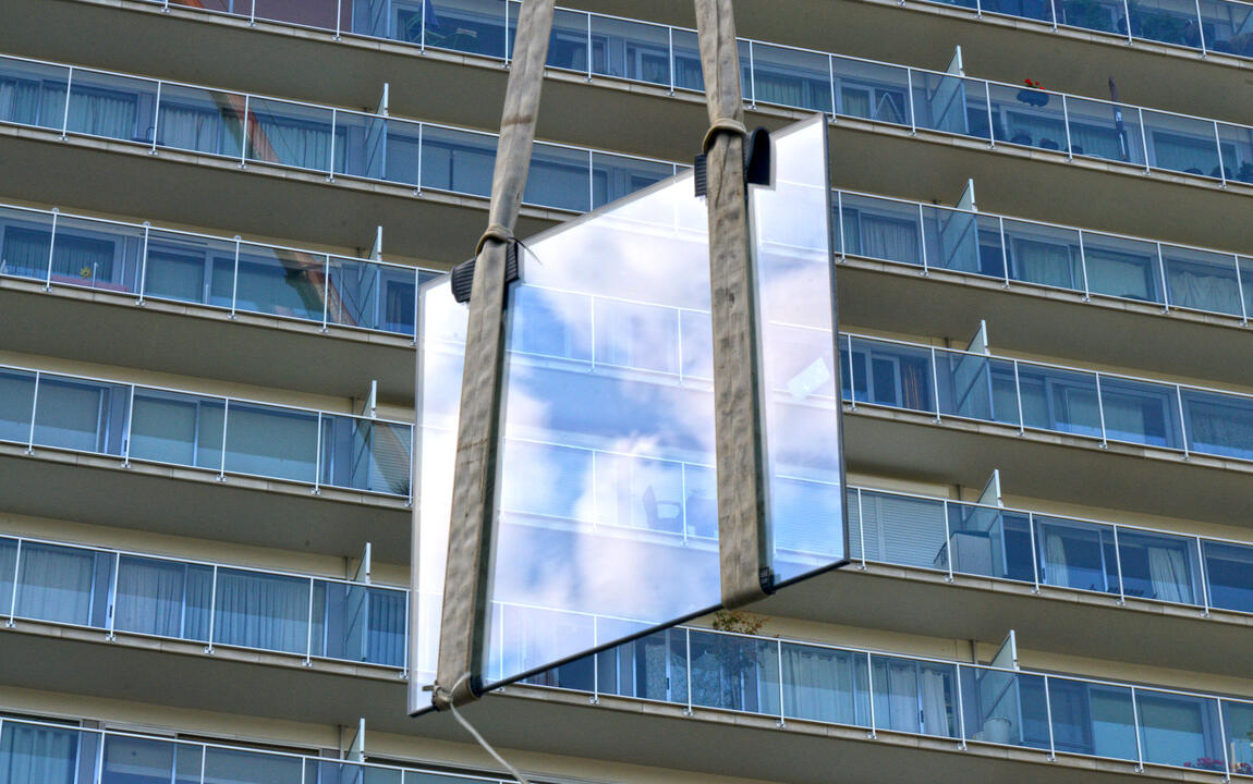 Een raam van een appartementsbouw wordt vervangen