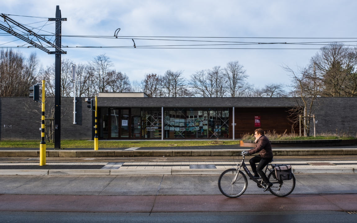 een vrouw fietst voorbij de tramhalte in Zwijnaarde