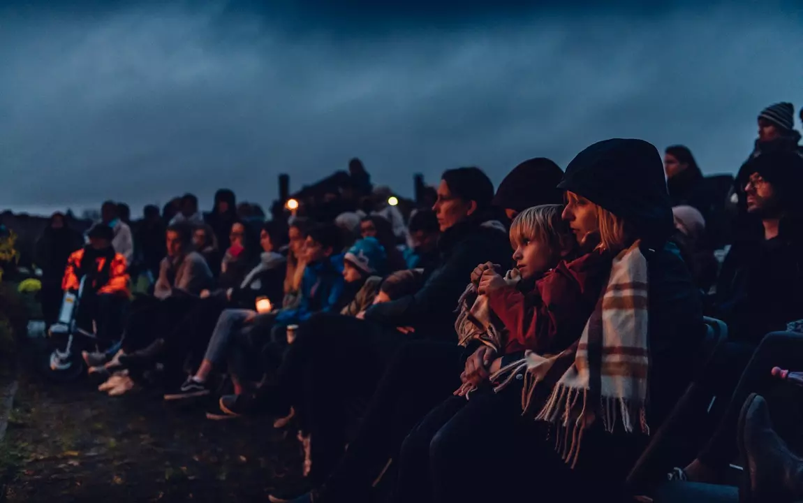 toeschouwers met lichtjes bij valavond op een begraafplaats 