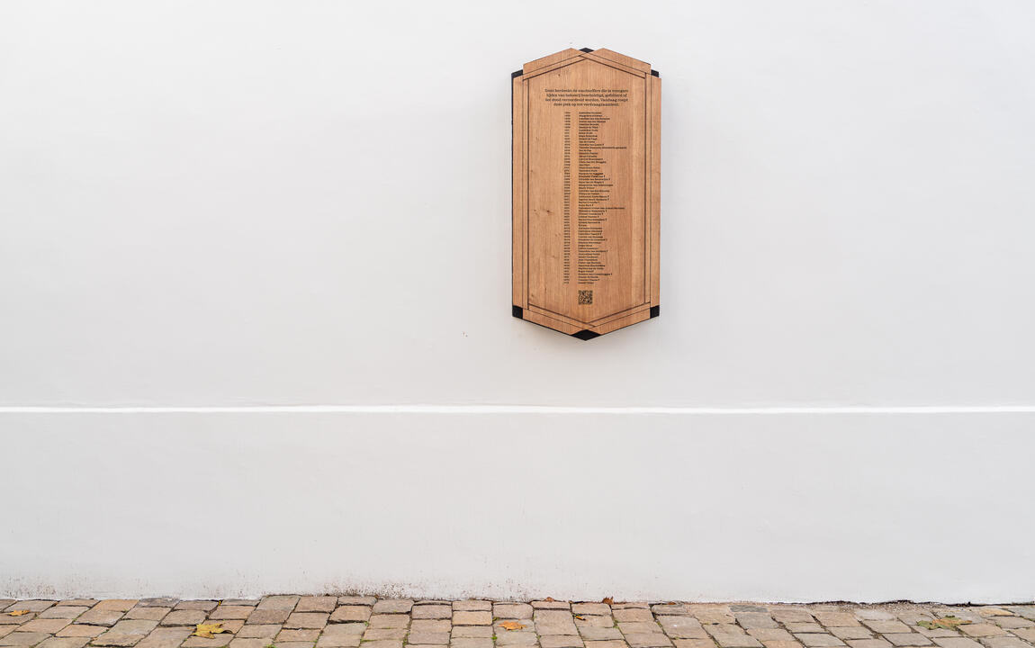 De gedenkplaat voor de slachtoffers van heksenvervolging hangt aan een witte muur in het Prinsenhof