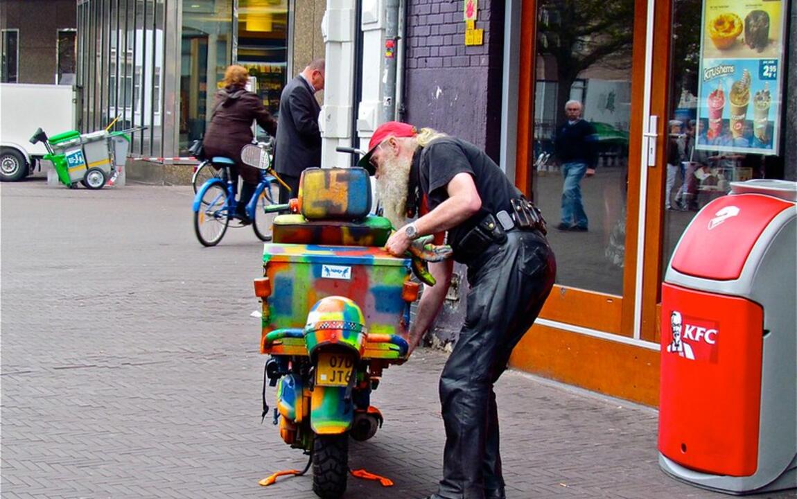 Man met kleurrijke bromfiets met laadbox