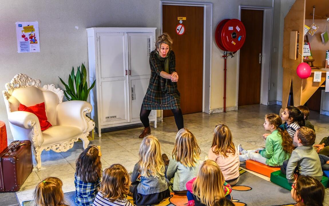 een actrice beeldt een verhaal uit, de kleuters luisteren aandachtig