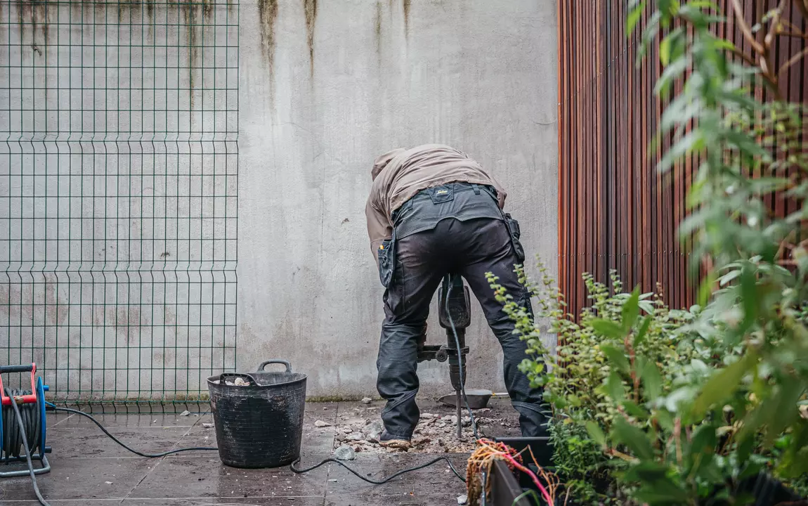 Man breekt tegels van stadskoer uit