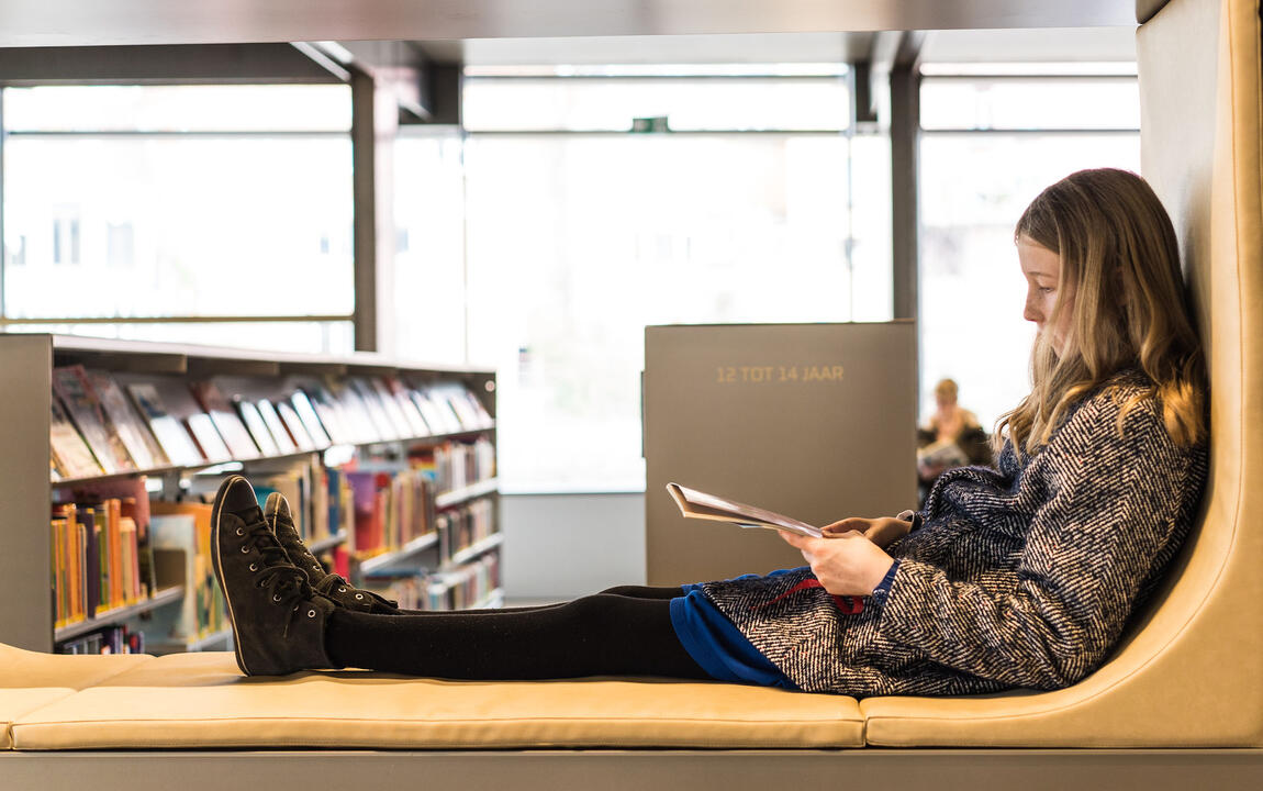 Kind met boek in bibliotheek De Krook