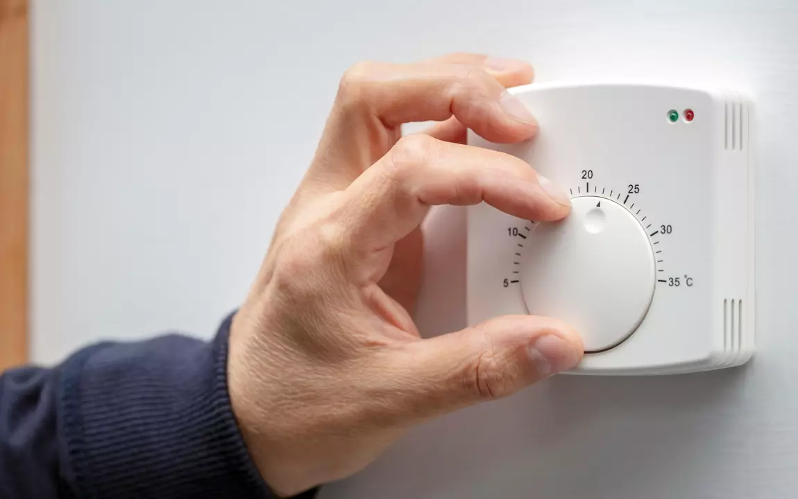 Hand draait aan knop van manuele thermostaat