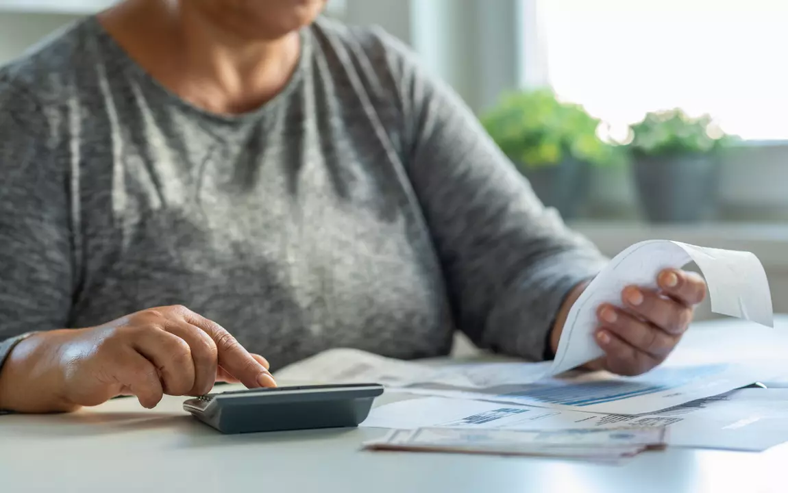 Vrouw bekijkt energierekening met rekenmachine
