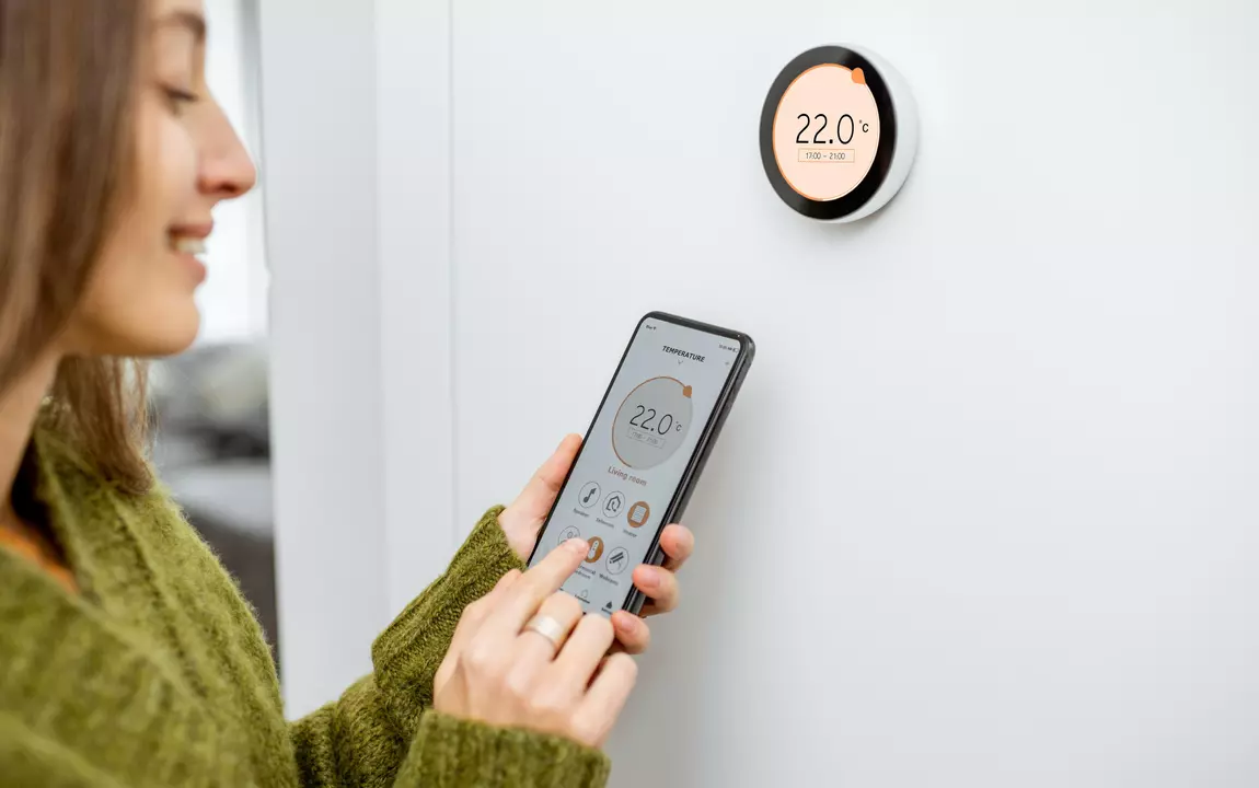 Vrouw stelt slimme thermostaat in met app op smartphone