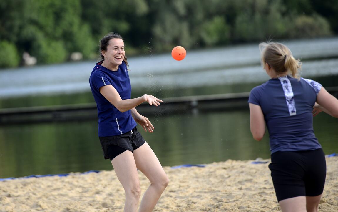 Twee mensen die op het strand spikeball spelen