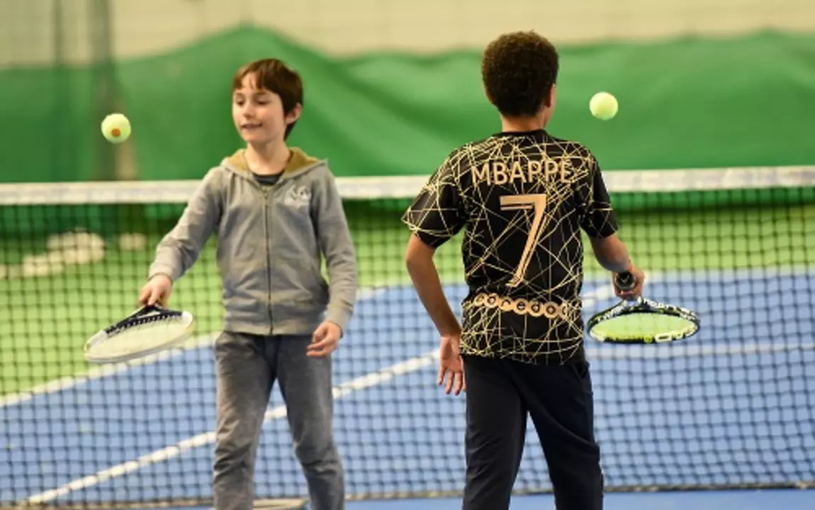 Twee kinderen die een tennisbal op een tennisracket laten botsen