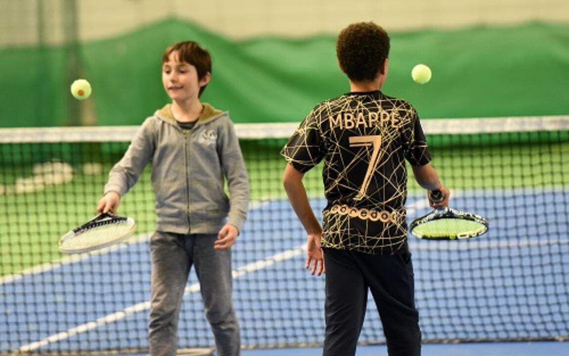 Twee kinderen die een tennisbal op een tennisracket laten botsen