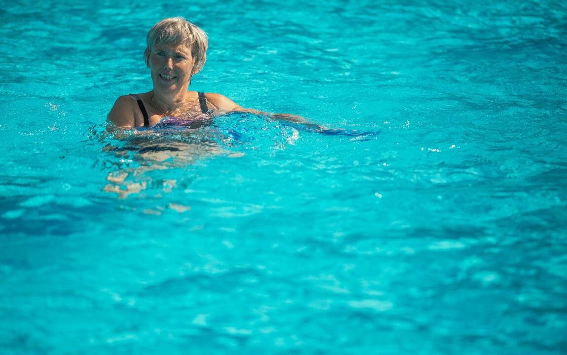 Een vrouw die in het zwembad staat en lacht