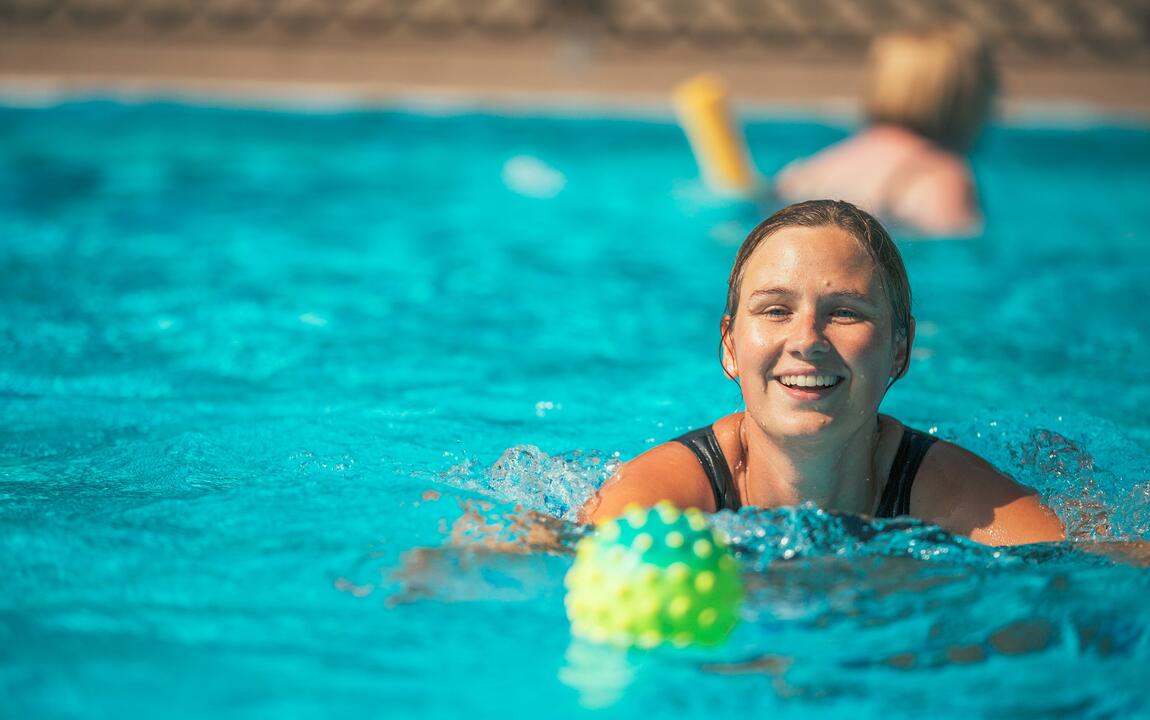 Een vrouw die zwemt met een kleine bal