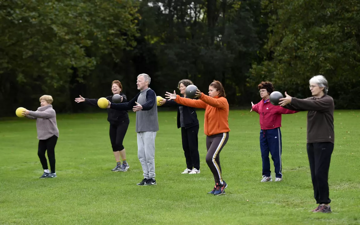 Sporters die met gestrekte armen en een bal in de hand oefeningen doen