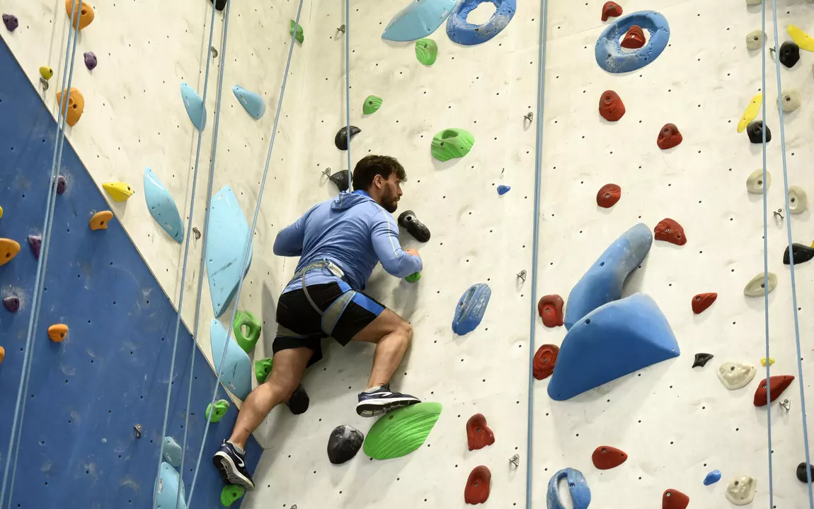 Een sporter die aan het indoor klimmen is op een mooie hoogte