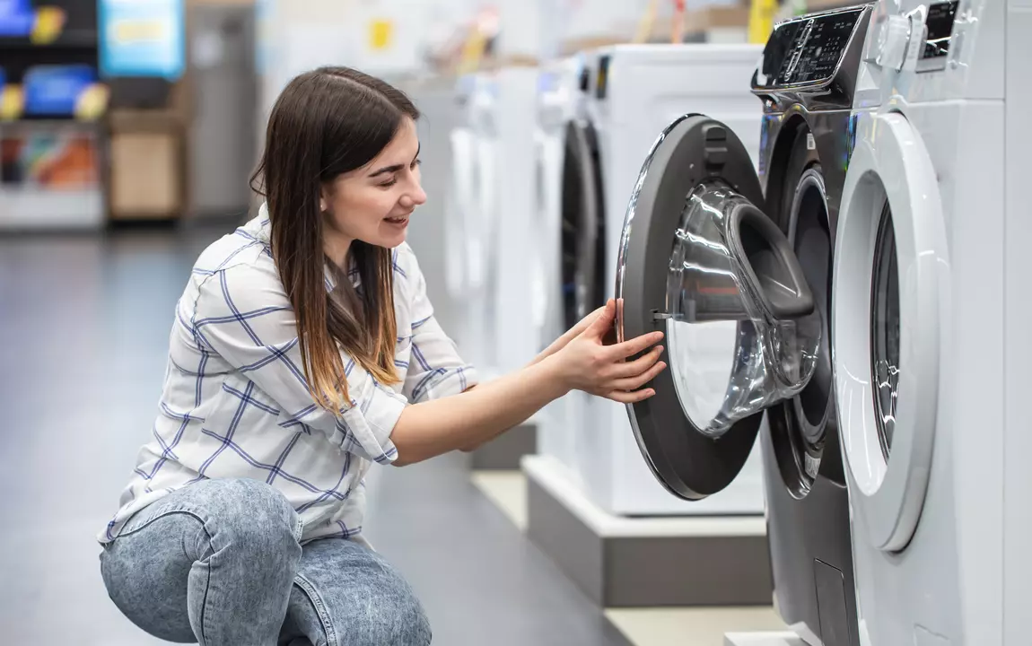 Jonge vrouw bekijkt een nieuwe wasmachine in een winkel
