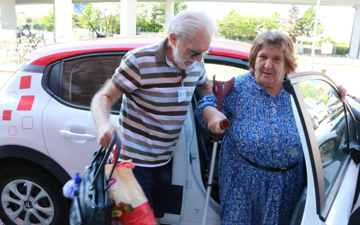 vervoersvrijwilliger helpt oudere dame uit auto