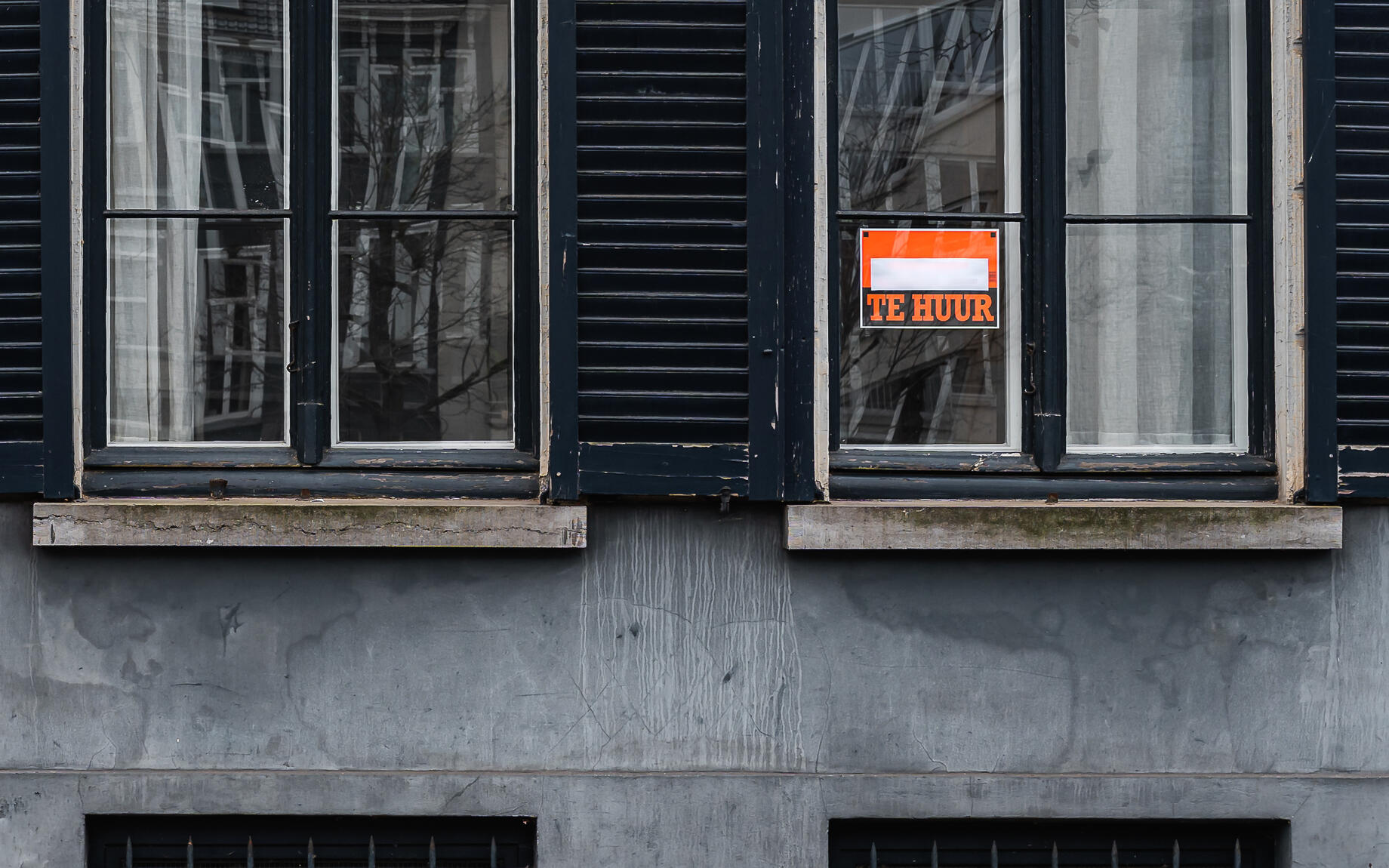 Papier met "te huur" hangt aan raam in Gent