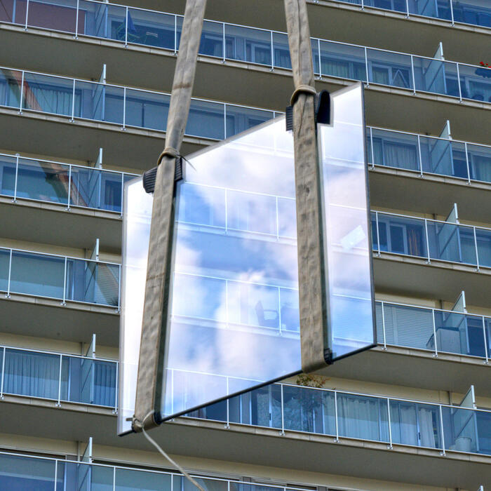 Een raam van een appartementsbouw wordt vervangen