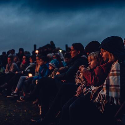 toeschouwers met lichtjes bij valavond op een begraafplaats 