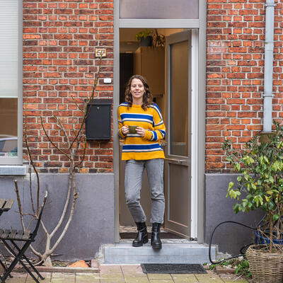 Vrouw staat in de deuropening van haar woning in Gent