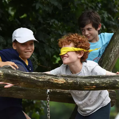Een kindje met blinddoek op een avontuurparcours