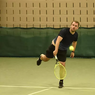 Man die met tennisracket de bal probeert terug te slaan