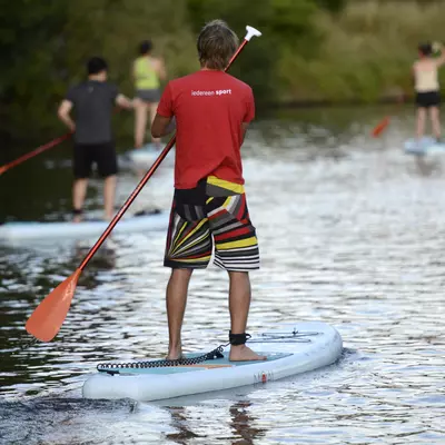 Lesgever van de sportdienst die op een SUP staat en vaart