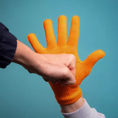 hand met oranje handschoen houdt vuist tegen