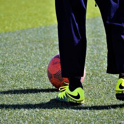 een voetballer met gele voetbalschoenen staat voor een voetbal