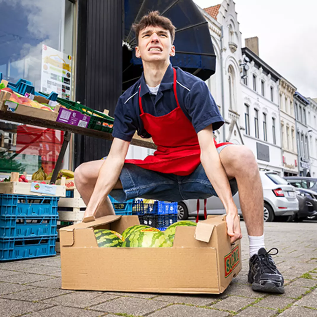 Kruidenier heft zware houten krat op