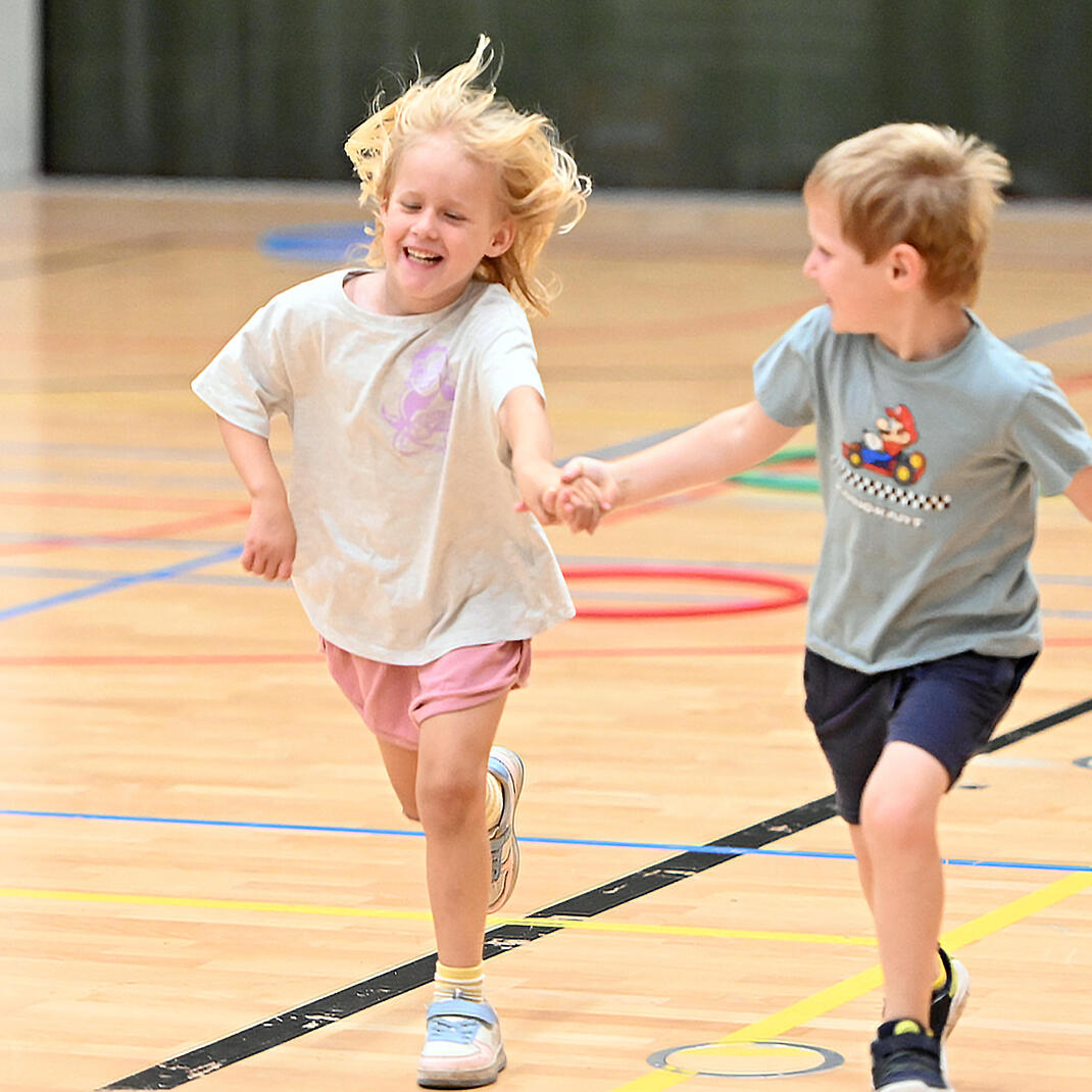 Twee kindjes die hand in hand aan het lopen zijn tijdens een sportkamp