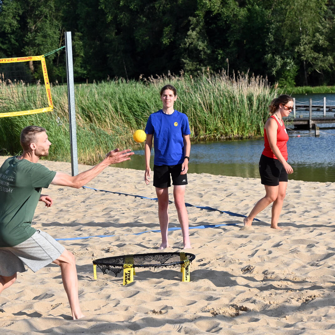 Sporters die op het strand van de Blaarmeersen spikeball spelen