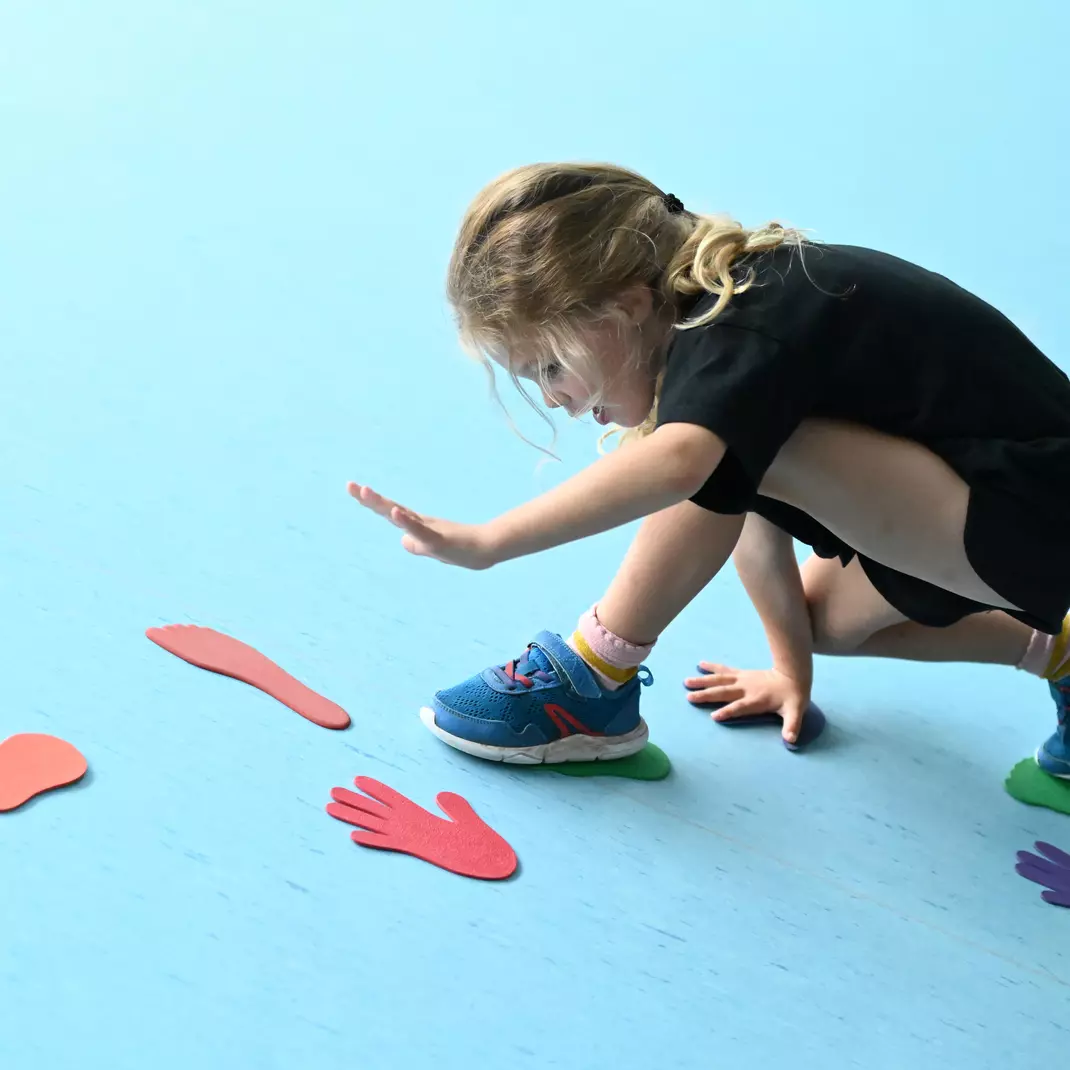 Een kindje dat met handjes en voetjes op figuurtjes stapt tijdens een sportkamp