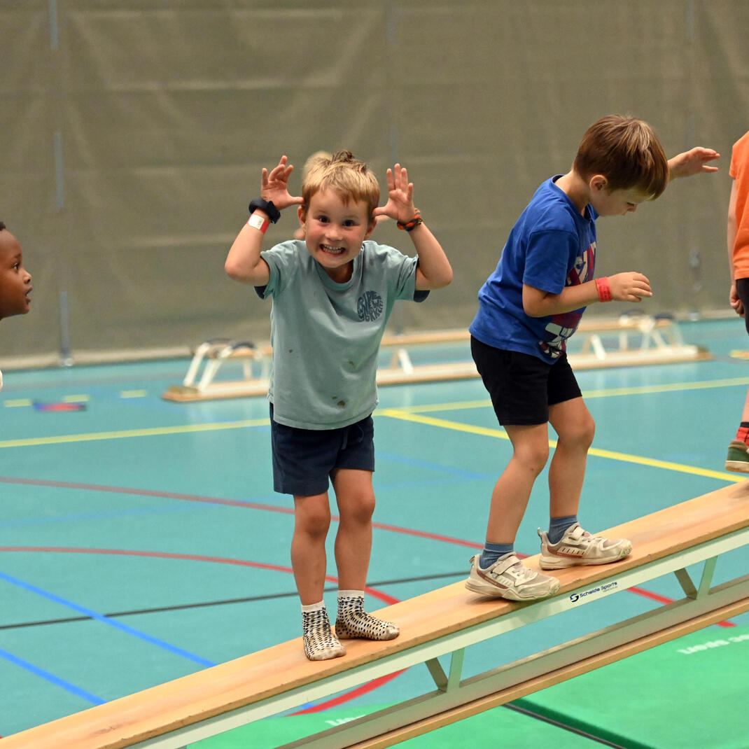 Kindjes die tijdens het sportkamp op een zweedse bank lopen