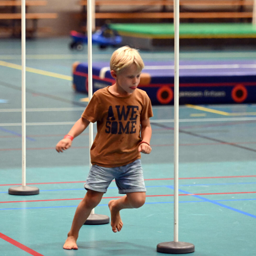 Kindje dat slalomt tussen palen op sportkamp