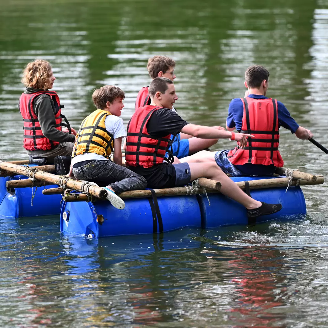 Jongeren die op een zelfgemaakt vlot varen op de vijver van de Blaarmeersen