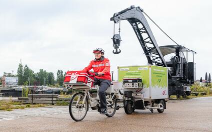 Een postbode met fietstrailer onderweg in Gent