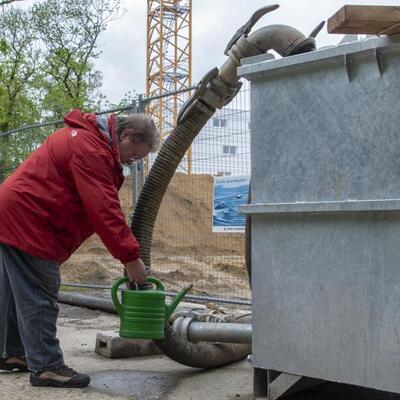 Een buurtbewoner tapt grondwater af op de werf bij stadsschool Het Tandwiel