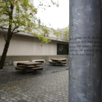 Verschillende pilaren aan de ingang van de campus bevatten elk een aantal zinnen van het gedicht
