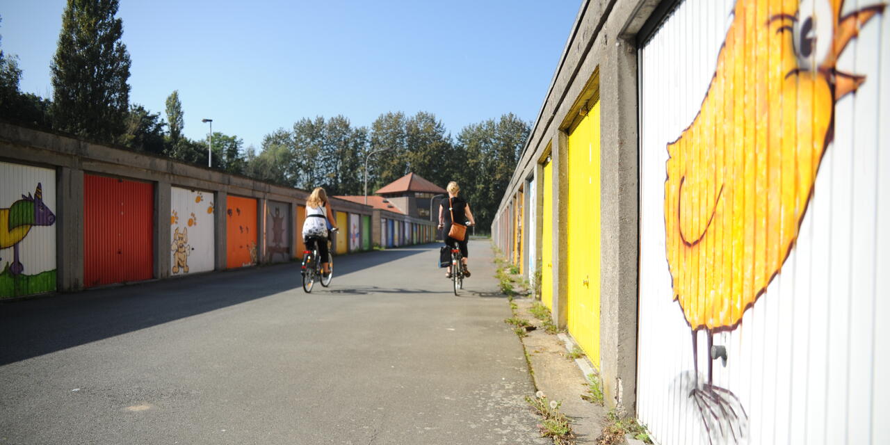 twee fietsers passeren enkele garageboxen