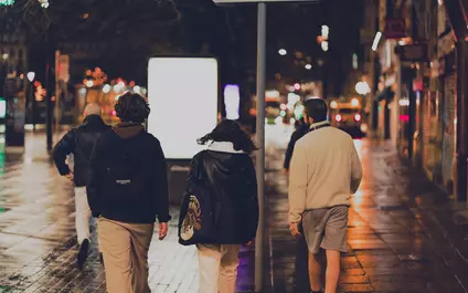 Drie jongeren lopen 's avonds in een stad